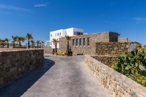 a stone wall with a building in the background at Splendid Mykonos Luxury Villas & Suites in Mikonos