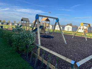 a playground with three swings in a park at The Snug - All Seasons Chalet Breaks in Leysdown-on-Sea
