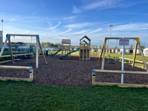 a playground with three swings in a park at The Snug - All Seasons Chalet Breaks in Leysdown-on-Sea