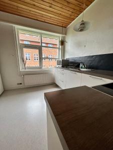 a kitchen with white cabinets and a large window at Overnatning med plads til mange in Holstebro +2 photos