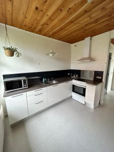 a kitchen with white appliances and a wooden ceiling at Overnatning med plads til mange in Holstebro