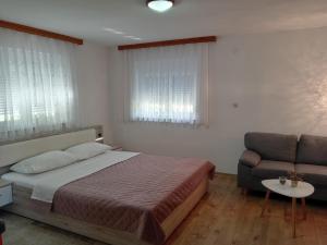 a bedroom with a bed and a couch and a chair at Apartments and Rooms Krizmanic in Smoljanac +38 photos