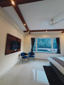 a bedroom with two chairs and a table and a bed at Kesari Hotel & Restaurant Near Kainchi Dham in Rāmgarh
