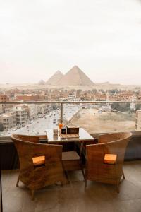 a table and chairs with a view of the pyramids at Petra Pyramids View in Al Kawāmil Qiblī