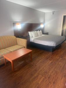 a hotel room with a bed and a couch and a table at Econo Lodge Naval Station Norfolk in Norfolk