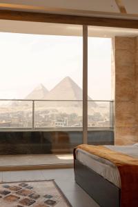 a bedroom with a large window with a view of pyramids at Petra Pyramids View in Al Kawāmil Qiblī +4 photos