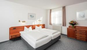 a bedroom with a large white bed and a dresser at Hotel zur Lichtenburg in Ostheim