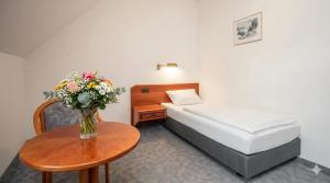 a small room with a bed and a table with a vase of flowers at Hotel zur Lichtenburg in Ostheim +1 photo