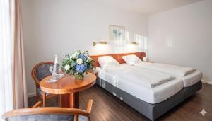 a hotel room with a bed and a table with flowers at Hotel zur Lichtenburg in Ostheim