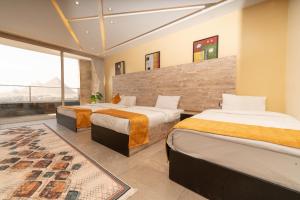 a hotel room with two beds and a large window at Petra Pyramids View in Al Kawāmil Qiblī