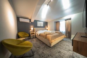 a bedroom with a bed and a yellow chair at Complex Rediu 54 Luxury Apartaments in Iaşi