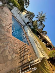 a swimming pool with stairs next to a stone wall at Farm km 68 Castelo Branco in Mairinque
