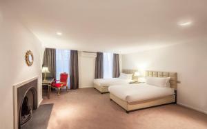a hotel room with two beds and a fireplace at Nottingham Place Hotel in London