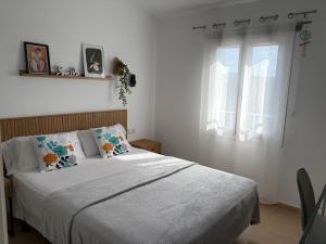 a bedroom with a bed with white sheets and a window at Garbí & Xaloc apartamentos in Cala Galdana