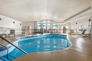a large swimming pool with blue water in a building at Red Roof Inn & Suites Tomah in Tomah