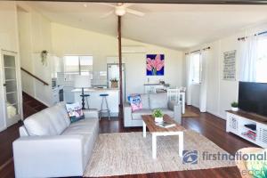 a living room with a white couch and a ceiling fan at 58 The Esplanade in Woodgate