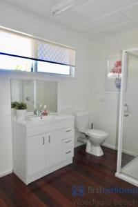a white bathroom with a toilet and a sink at 58 The Esplanade in Woodgate +18 photos