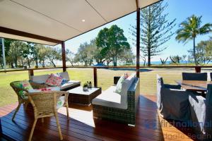 a porch with chairs and a table with a view of a field at 58 The Esplanade in Woodgate