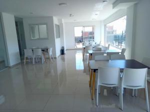 a dining room with white tables and white chairs at Edificio Leonardo Premium Centro Las Heras in Villa Carlos Paz