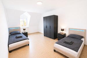 a bedroom with two beds and a black cabinet at LETA Homes - Komfortable FeWo mit Traumbalkon mit flexiblem, Self-Check-In & eigenen Parkplätzen in Straubing