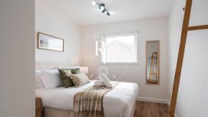 a white bedroom with a bed and a window at The Den at Abernethy in Peterhead +2 photos