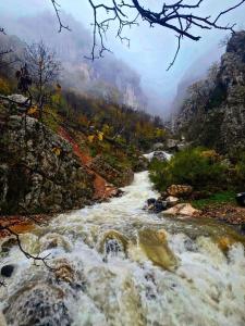 a painting of a river in the mountains at Bujtina Shpella e Plakës Çerçan in Librazhd
