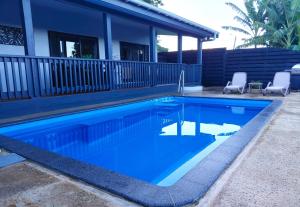 a swimming pool with two chairs in front of a house at Pool Villa No 10 in Rarotonga
