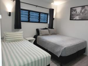a bedroom with two beds and a window at Pool Villa No 10 in Rarotonga +19 photos