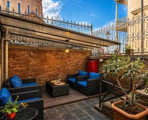 a rooftop patio with blue furniture and a brick wall at Vernisa Hotel in Tbilisi City