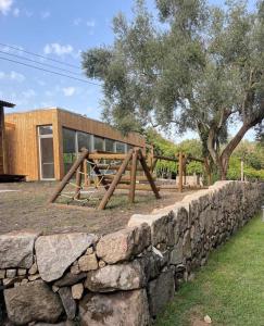 a stone wall with a wooden swing set in front of a building at Recanto da Malhadoira in Currais
