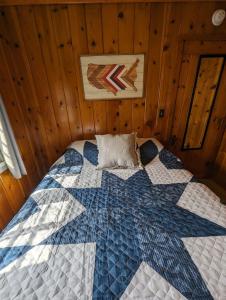 a bed in a wooden room with a quilt on it at 2BR 1BA Cabin #3 Riverside Point Resort in Park Rapids