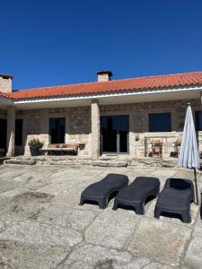 two chairs and an umbrella in front of a building at Quinchoso dos Bentos in Vila Pouca de Aguiar