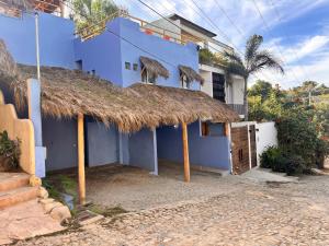 a blue house with a thatched roof at Cozy Little Apartment in Sayulita