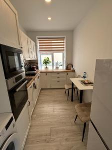 a kitchen with white cabinets and a table at Vecpilsētas apartaments in Cēsis +8 photos