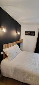 a bedroom with a white bed with a black wall at Le Désiré in Arras