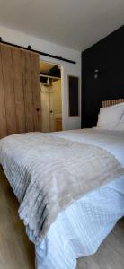 a white bed in a bedroom with a black wall at Le Désiré in Arras