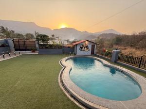 a swimming pool in a yard with a sunset in the background at AG ViLLA NERAL in Neral
