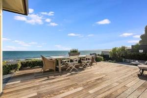 a wooden deck with a table and chairs and the ocean at Salty Sunrise in Aptos