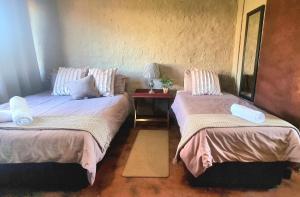 a room with two beds and a table with a lamp at Die Windpomp Bosveld in Ellisras +4 photos