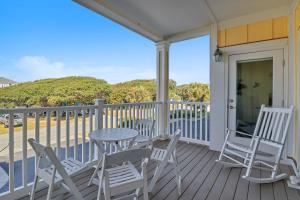 a porch with a table and chairs and a view of the ocean at The Dunes by Oak Island Accommodations in Oak Island