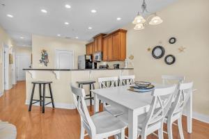 a kitchen and dining room with a white table and chairs at The Dunes by Oak Island Accommodations in Oak Island