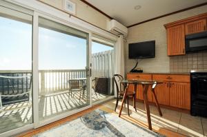 a kitchen with a balcony with a table and a television at Wavecrest Resort in Montauk