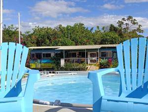 two blue chairs sitting next to a swimming pool at The Dreamcatcher House Glamping & Cabins Sarchí in Sarchí