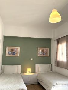 two beds in a bedroom with a green wall at Maria Mare in Myrtos