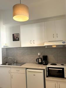 a kitchen with white cabinets and a sink and a stove at Maria Mare in Myrtos