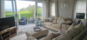 a living room with couches and a television and a balcony at The Key is Under the Mat in Polperro