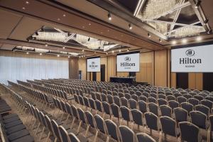 an auditorium with rows of chairs and two screens at Hilton Belgrade in Belgrade