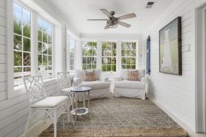 a screened in porch with chairs and a ceiling fan at Beach Bungalow Upper Unit Steps To Shore in Isle of Palms