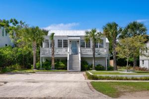 a white house with palm trees in front of it at Beach Bungalow Upper Unit Steps To Shore in Isle of Palms
