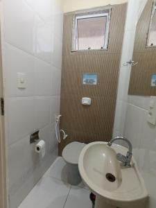 a white bathroom with a toilet and a sink at Apartamento Castelhanos Anchieta in Anchieta +18 photos